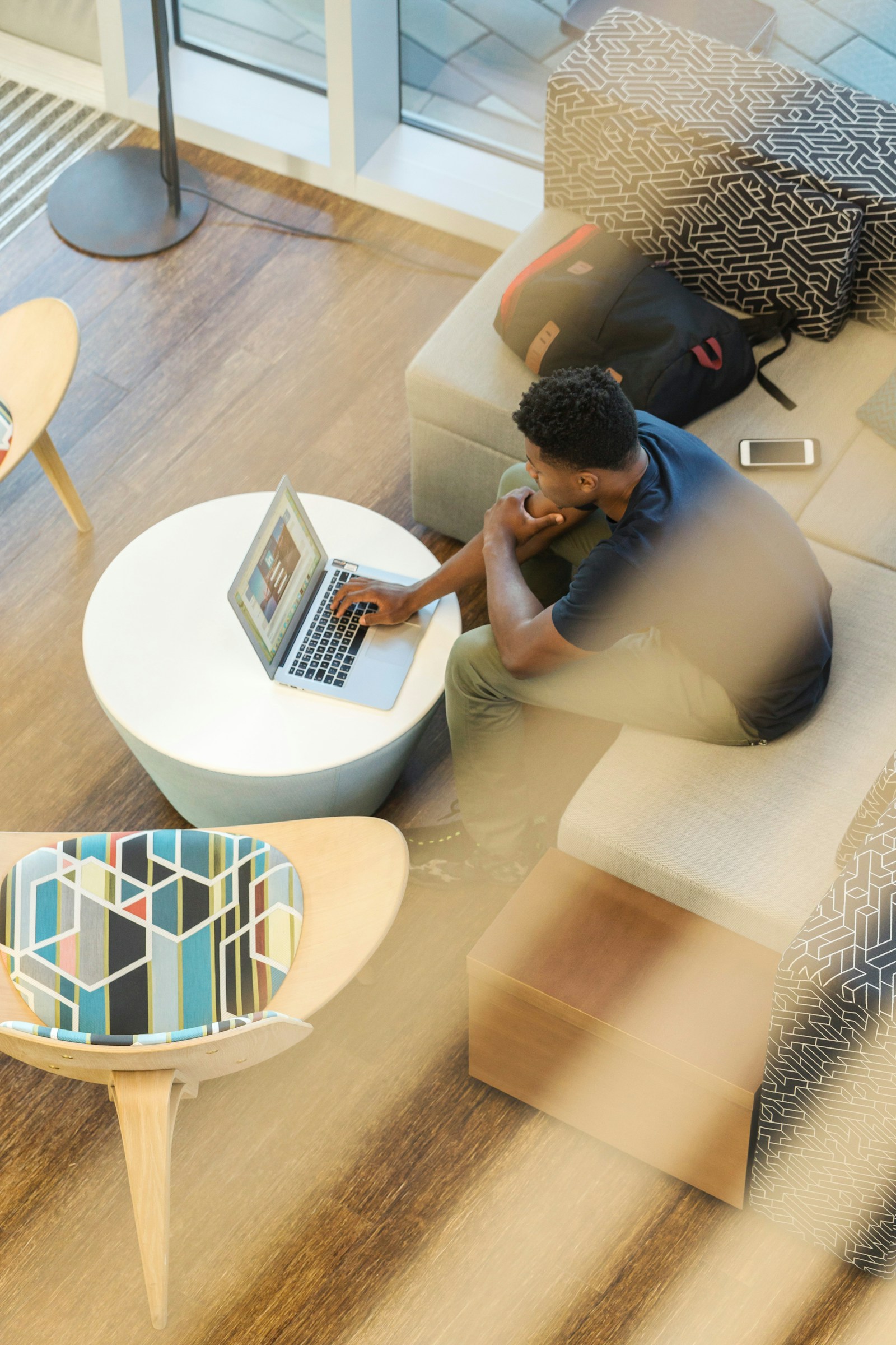 A young man studying on a laptop in a light-filled lounge