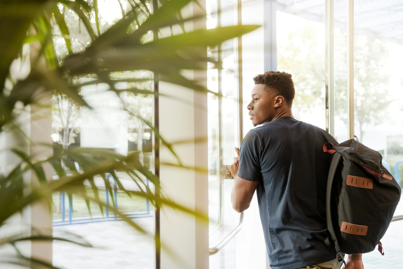 A young man with a backpack looking toward a bright learning space